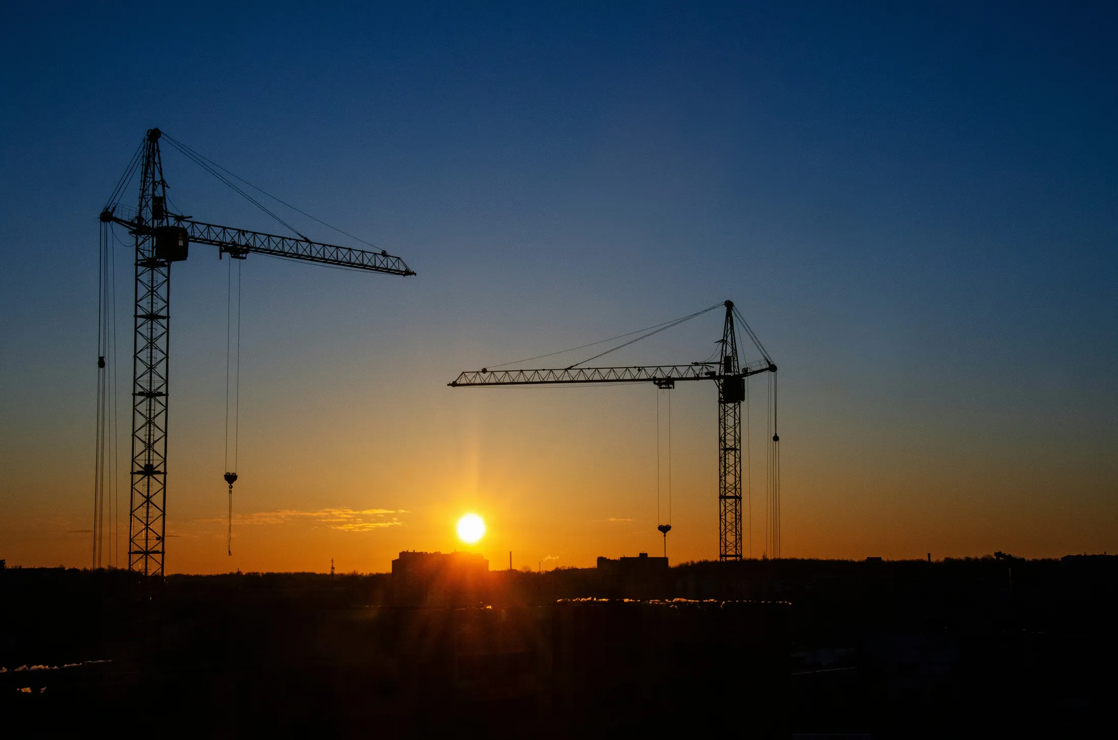 Bouwplaats met kranen bij zonsondergang